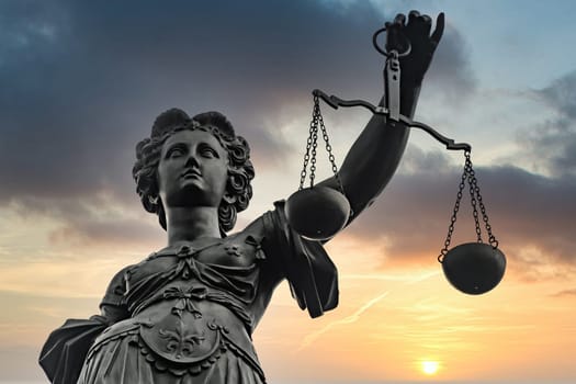 Symbol of Justizia figure in Frankfurt with dramatic sunrise background