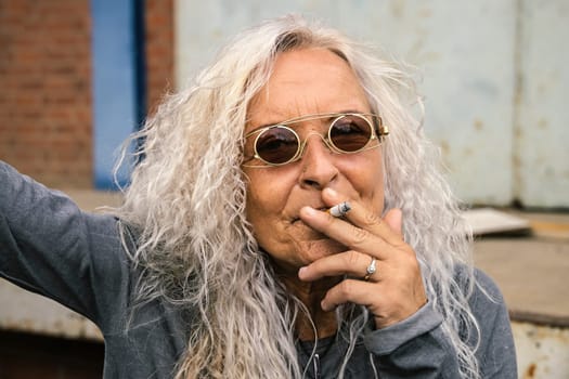 Beautiful woman with long bright curly hair Woman pulls on a cigarette.