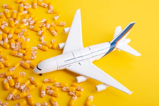 Concept Travel Sickness - Toy Airplane with yellow pills on yellow background