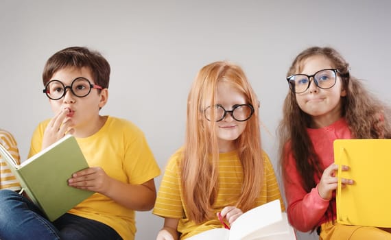 Group of children sitting indoors and reading books.. Concept of education and friendship.