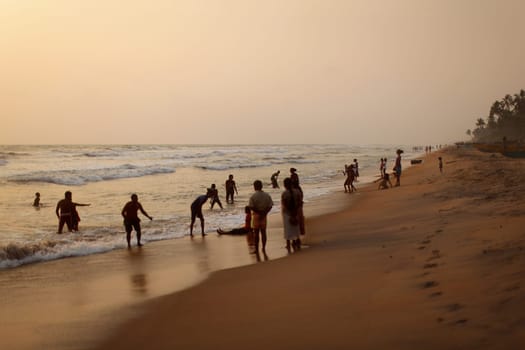 Kalutara, Sri Lanka - April 15, 2017: Silhouettes of locals, mostly kids playing on the beach and in sea after sunset.