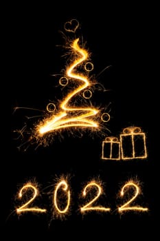 Merry christmas greeting card. Sparkling firework christmas tree with presents and number 2022.