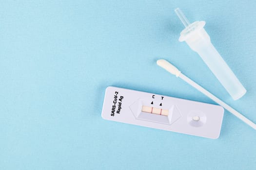 Positive result in rapid Ag Covid test on blue background. Copy space for text. Tested positive.