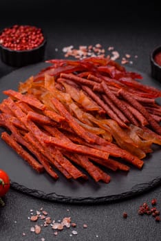 Jerky, dried fish in the form of sticks with salt, spices and herbs on a dark concrete background