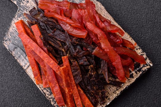 Jerky, dried fish in the form of sticks with salt, spices and herbs on a dark concrete background