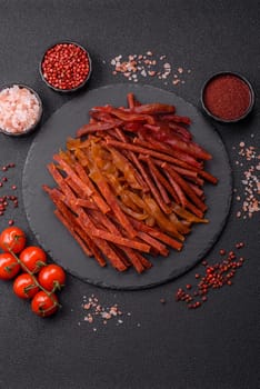 Jerky, dried fish in the form of sticks with salt, spices and herbs on a dark concrete background