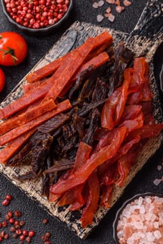 Jerky, dried fish in the form of sticks with salt, spices and herbs on a dark concrete background