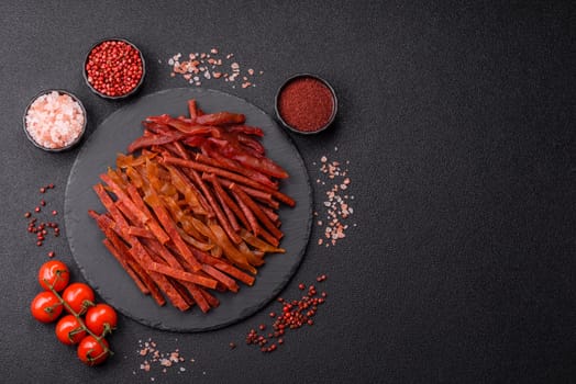 Jerky, dried fish in the form of sticks with salt, spices and herbs on a dark concrete background