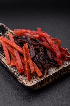 Jerky, dried fish in the form of sticks with salt, spices and herbs on a dark concrete background