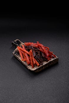 Jerky, dried fish in the form of sticks with salt, spices and herbs on a dark concrete background