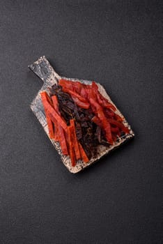 Jerky, dried fish in the form of sticks with salt, spices and herbs on a dark concrete background