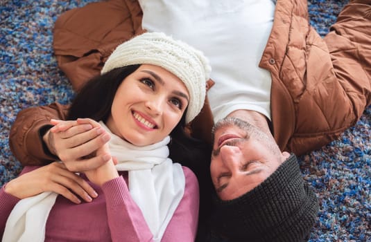 Cheerful man and woman lying on living room floor. Young couple celebrating winter Christmas at home