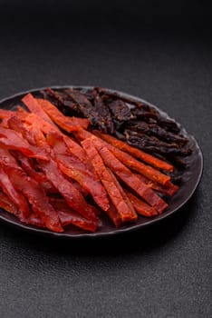 Jerky, dried fish in the form of sticks with salt, spices and herbs on a dark concrete background