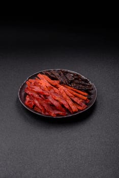 Jerky, dried fish in the form of sticks with salt, spices and herbs on a dark concrete background