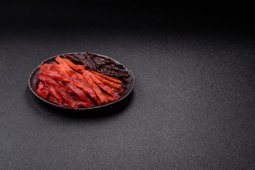 Jerky, dried fish in the form of sticks with salt, spices and herbs on a dark concrete background