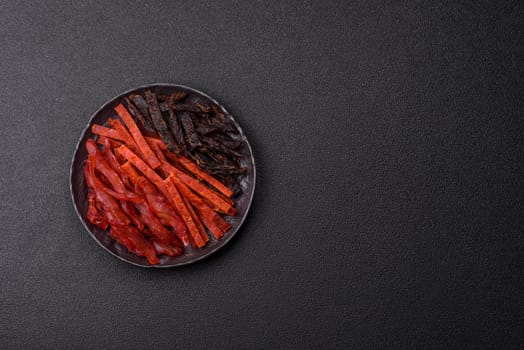Jerky, dried fish in the form of sticks with salt, spices and herbs on a dark concrete background