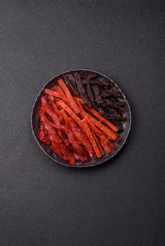 Jerky, dried fish in the form of sticks with salt, spices and herbs on a dark concrete background