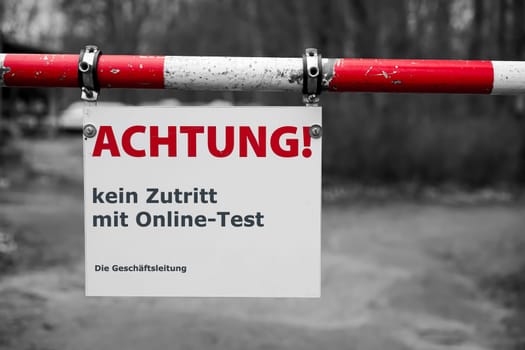 Restricted access at the barrier to a company site in germany during the Corona Pandemic. Translation: Attention, no access with online Corona Test. The Management.