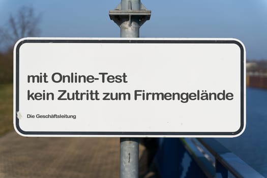 Restricted access at the entrance to a company site in germany during the Corona Pandemic. Translation: with online test no access to the company premises. The Management.