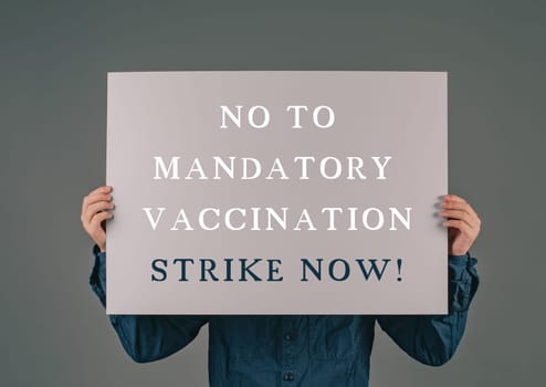 The words stop mandatory vaccination are standing on a paper, protest anti covid-19 vaccine, strike, health care