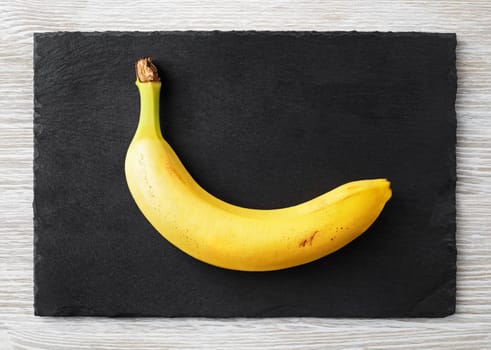 Delicious ripe banana on stone board. Flat lay.
