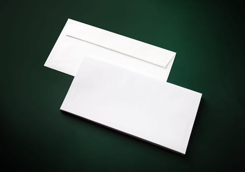 Two blank white envelopes on green background. Copy space.
