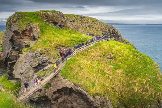 Ballycastle, August 2019 Group of people and families crossing Carrick a Rede rope bridge, Wild Atlantic Way, Northern Ireland