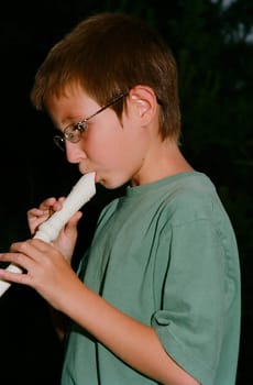 Young boy playing a recorder musical instrument