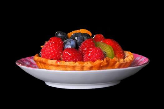 Fresh fruit tart isolated over black background