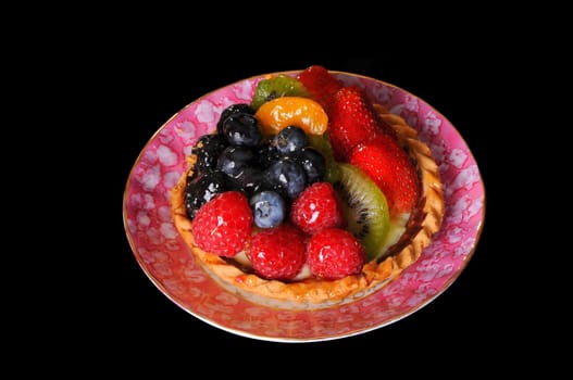 Fresh fruit tart isolated over black background