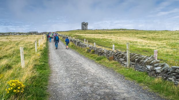 Group of people on road leading to Moher Tower at Hags Head in Cliffs of Moher, popular tourist attraction, Wild Atlantic Way, County Clare, Ireland