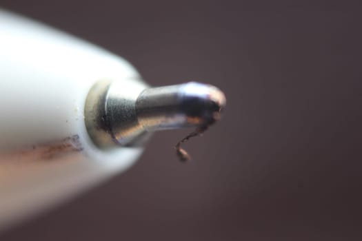 Macro photo of ballpoint pen tip with dark grey background. Extreme macro image of metal ballpoint pen on grey background.