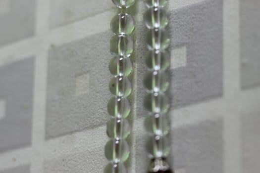 Macro photograph with selective focus of glass shiny prayer beads or rosary with copy space for text. Religion concept of ramadan or Eid for muslims.