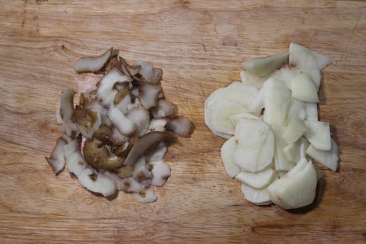 Chopped potato slices with peelings on a wooden cutting board