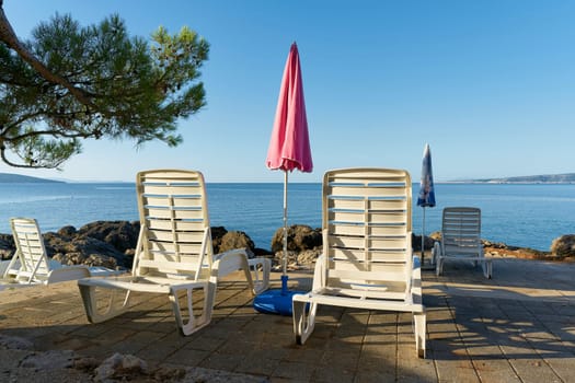 Parasol and sun loungers on the coast of the Adriatic Sea near the town of Krk in Croatia