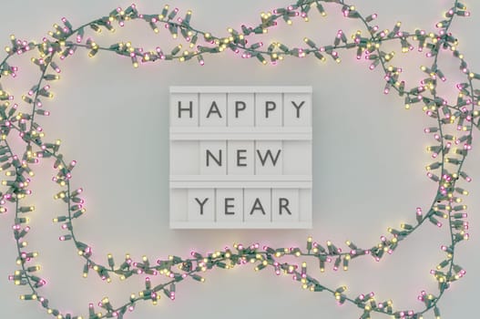 3d illustration. Happy New Year Text Light Box and Glowing light bulbs Christmas and New Year on white background . Copy Space For Message.