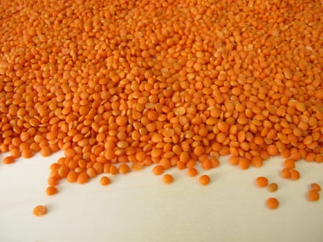 Red lentils distributed flatly on a wooden board