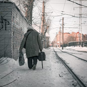 17th of November 2021, Russia, Tomsk, an old woman go along rialway with bags