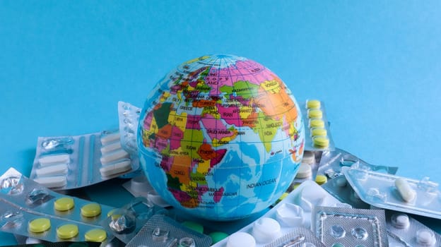 Ukraine, Kiev - April 14, 2020. The concept of a pandemic and global viral infection in America, Europe and around the world. Model of the globe and pills. A planet with packs of antiviral drugs