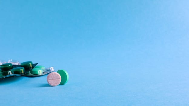 Two packs of pills and one round pill to the side on a blue background with copy space. antiviral tablets for pneumonia and bacterial infection. medicines and wellness treatments