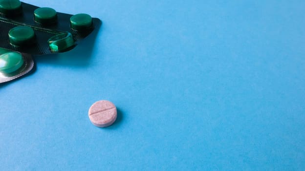 Two packs of pills and one round pill to the side on a blue background with copy space. antiviral tablets for pneumonia and bacterial infection. medicines and wellness treatments
