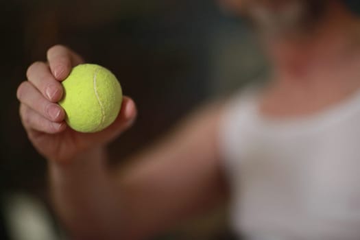 yellow tennis ball in tennis player's hand soft focus