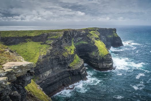 Turquoise coloured waves of Atlantic Ocean crashing on iconic Cliffs of Moher, popular tourist attraction, Wild Atlantic Way, County Clare, Ireland
