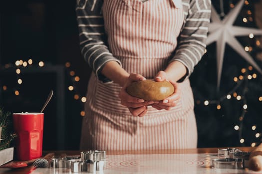 Merry Christmas, Happy New Year. Gingerbread cooking, cake, biscuit or strudel baking. Woman in apron is kneading dough. Girl gently holding, creases, cook and bake. Christmas decorations at kitchen