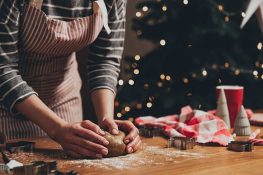 Merry Christmas, Happy New Year. Gingerbread cooking, cake, biscuit or strudel baking. Woman in apron is kneading dough. Girl gently holding, creases, cook and bake. Christmas decorations at kitchen