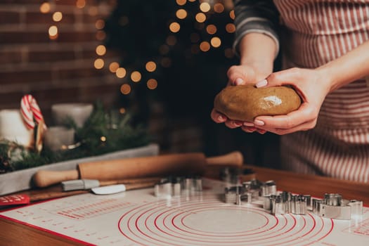 Merry Christmas, Happy New Year. Gingerbread cooking, cake, biscuit or strudel baking. Woman in apron is kneading dough. Girl gently holding, creases, cook and bake. Christmas decorations at kitchen