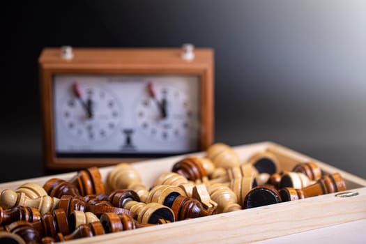 The Chess pieces on a board and a chess clock on a dark background