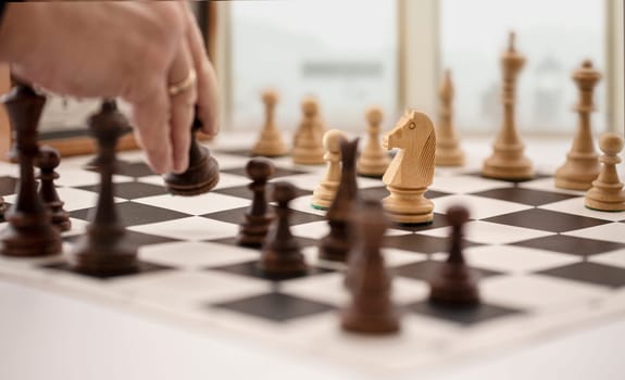 The chess board with clock and figures in front of a blurry window