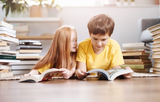 Two cute children lying on the floor indoors with books on the head. Concept of hobby and education.
