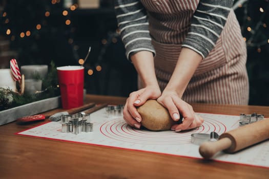 Merry Christmas, Happy New Year. Gingerbread cooking, cake, biscuit or strudel baking. Woman in apron is kneading dough. Girl gently holding, creases, cook and bake. Christmas decorations at kitchen